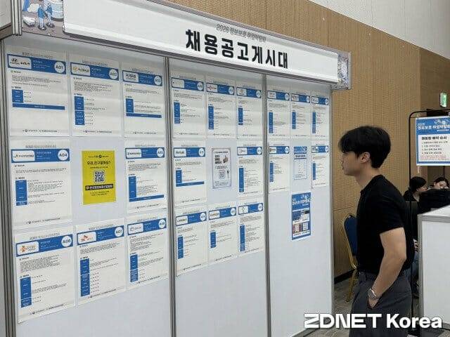 정보보호 분야 채용 공고 게시판을 확인하고 있는 박람회 참가자.