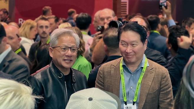 지난 3월 미국 새너제이에서 개막한 글로벌 기술 콘퍼런스 'GTC 2026'(GPU Technology Conference 2026)에서 SK하이닉스 전시 부스를 찾은 엔비디아 젠슨 황 CEO(왼쪽 가운데)와 SK그룹 최태원 회장이 대화를 나누고 있다. 뉴시스 제공