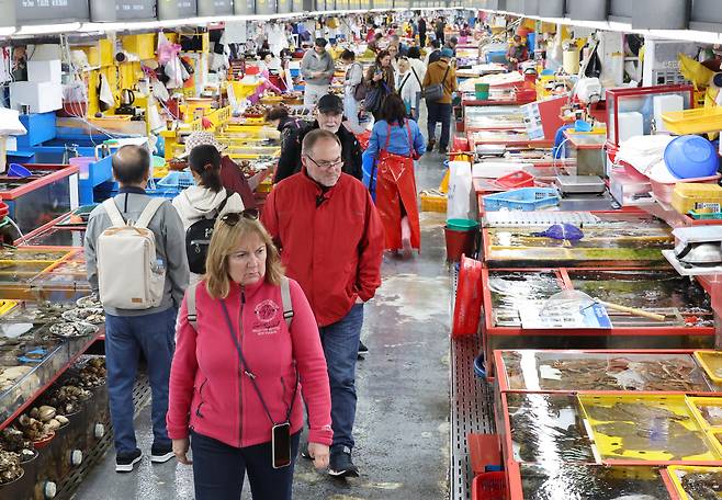 Foreign tourists browse fresh seafood at Jagalchi Market in Jung District, Busan, on April 8. [JOONGAINGILBO]