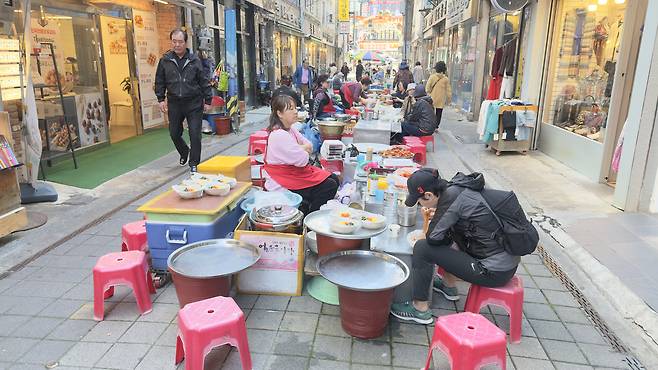 Visitors try simple yet comforting dishes at a row of stalls tucked inside an alley at Gukje Market on May 6.[WOO JI-WON]