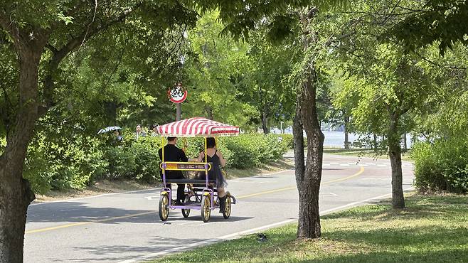 A couple rides on a family-sized bike at Yeouido Hangang Park on May 18. [WOO JI-WON]
