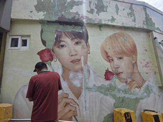 A mural of BTS members Jungkook and Jimin at Gamcheon Culture Village is undergoing restoration. [JIN EUN-SOO]