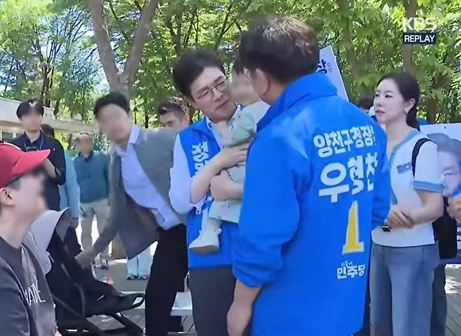 더불어민주당 정원오 서울시장 후보와 우형찬 양천구청장 후보가 31일 양천구 파리공원에서 아기에게 대화를 시도하고 있다. KBS 유튜브 갈무리