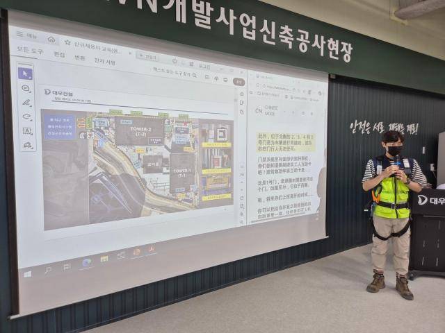 대우건설 관계자가 과천 G-TOWN 개발사업 신축공사 현장에서 외국인 근로자를 위한 AI 번역기 기능에 대해 교육 중이다. [사진=대우건설]