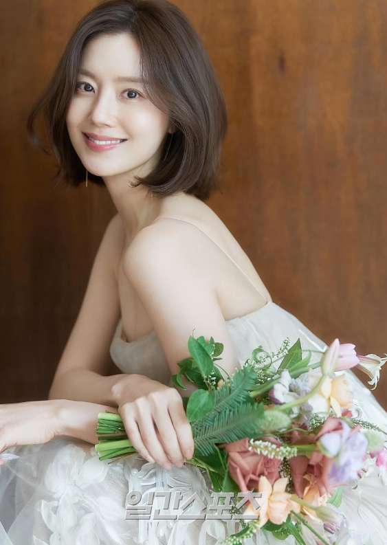 On February 2, Moon Chae-won posted several photoshoot photos on her social media without any comment.In one of the photos, Moon Chae Won wore her hair in a fresh short hairstyle. Wearing a skin-tone string dress that reveals her slender shoulders, she holds a bouquet of colorful fresh flowers and smiles softly as she looks off into the distance. The natural and lovely mood of the image is admirable.It is also the epitome of an authentic wedding dress. Moon Chae-won looks elegant in an off-the-shoulder, long-sleeved gown with elaborate lace embellishments against a dark background. Her long, see-through veil, the white bouquet in her arms, and her downward-facing smile complete the mysterious and luxurious atmosphere of a classic painting.