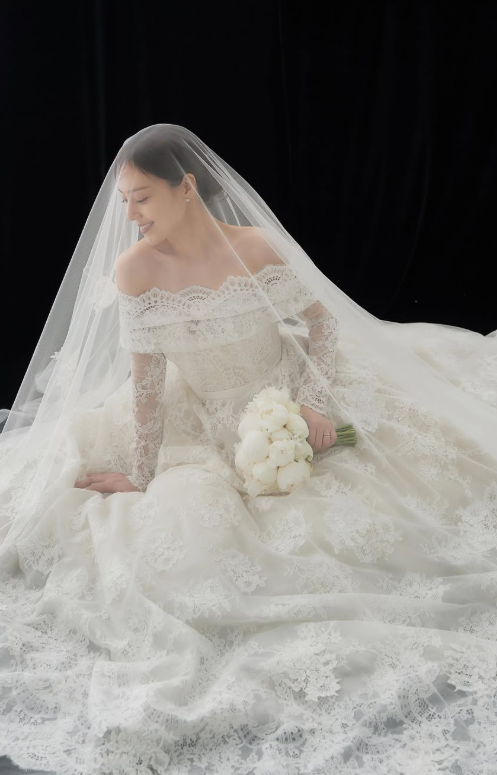 On February 2, Moon Chae-won posted several photoshoot photos on her social media without any comment.In one of the photos, Moon Chae Won wore her hair in a fresh short hairstyle. Wearing a skin-tone string dress that reveals her slender shoulders, she holds a bouquet of colorful fresh flowers and smiles softly as she looks off into the distance. The natural and lovely mood of the image is admirable.It is also the epitome of an authentic wedding dress. Moon Chae-won looks elegant in an off-the-shoulder, long-sleeved gown with elaborate lace embellishments against a dark background. Her long, see-through veil, the white bouquet in her arms, and her downward-facing smile complete the mysterious and luxurious atmosphere of a classic painting.