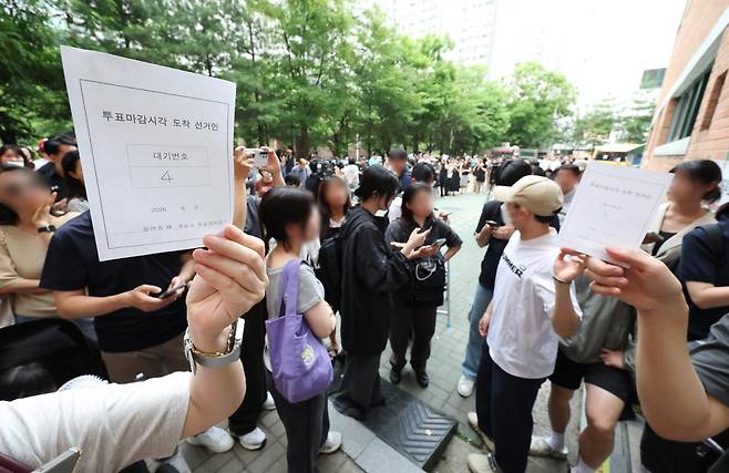 6·3 지방선거 본투표일인 3일 서울 송파구 잠실2동 6투표소에서 투표용지 부족으로 대기하던 한 유권자가 마감 시간 후 대기 번호표를 들어 보이고 있다. 연합뉴스
