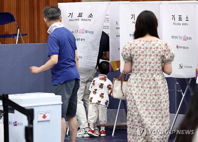 ‘아빠 투표 다 했어요?’ (서울=연합뉴스) 윤동진 기자 = 제9회 전국동시지방선거일인 3일 서울 잠전초등학교 체육관에 마련된 잠실본동 제4,5,6투표소에서 한 어린이가 투표하는 아빠를 보고 있다. 2026.6.3 mon@yna.co.kr