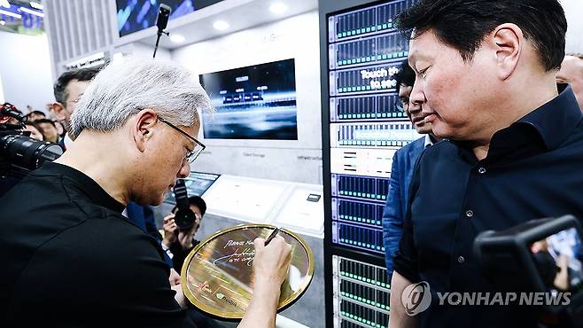 협력 제품 전시물에 사인 남기는 젠슨 황 엔비디아 CEO (서울=연합뉴스) 젠슨 황 엔비디아 CEO가 2일 대만 타이베이에서 개막한 '컴퓨텍스 2026'에 참석, SK하이닉스 전시 부스에 소개된 양사의 협력 제품 전시물에 사인을 남기고 있다. 2026.6.2 [SK하이닉스 제공. 재판매 및 DB 금지] photo@yna.co.kr
