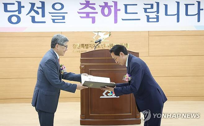 당선증 받은 우상호 강원도지사 당선인 (춘천=연합뉴스) 양지웅 기자 = 우상호 강원도지사 당선인이 4일 강원 춘천시 강원특별자치도선거관리위원회에서 열린 제9회 전국동시지방선거 당선증 전달식에서 김재호 도 선관위원장으로부터 당선증을 전달받고 있다. 2026.6.4 yangdoo@yna.co.kr