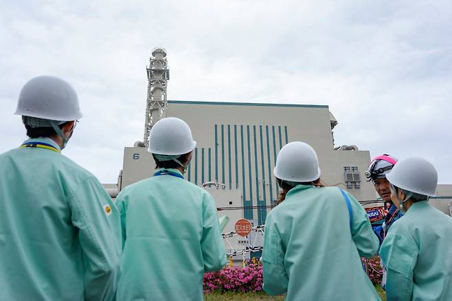지난 1일 일본 니가타현 가리와촌의 가시와자키·가리와 원자력발전소에서 진행된 기자간담회에서 취재진과 도쿄전력 직원들이 6호기 원자로 건물 앞에 서 있다./연합뉴스
