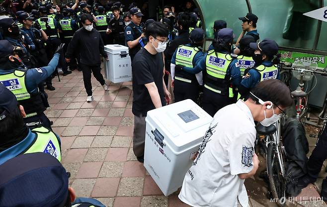 (서울=뉴스1) 김도우 기자 = 5일 '투표용지 부족' 사태가 발생한 서울 송파구 잠실7동 제2투표소 앞에서 서울시선관위 관계자들이 투표함을 이송하고 있다. 2026.6.5/뉴스1  Copyright (C) 뉴스1. All rights reserved. 무단 전재 및 재배포,  AI학습 이용 금지. /사진=(서울=뉴스1) 김도우 기자