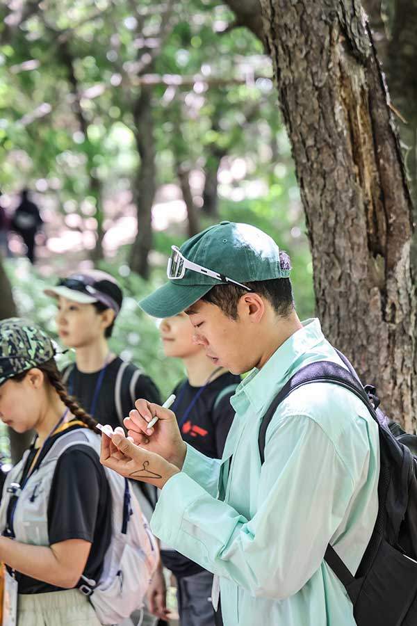 숲해설을 경청하고 메모하는 참가자들.