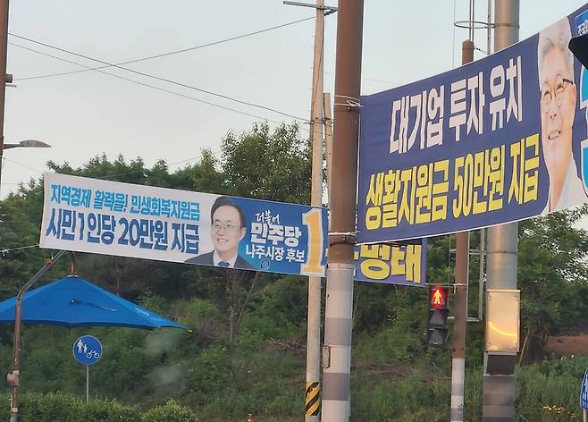 나주시장 선거 본선에서 맞붙은 민주당 윤병태 후보(당선인)는 시민 1인당 20만 원의 민생회복지원금을, 조국혁신당 김덕수 후보는 연간 1인당 50만 원의 '생활안정지원금'을 주겠다고 공약했다. 나주시내 가로변에 이 같은 내용을 담은 현수막이 걸려있다. ⓒ시사저널 정성환