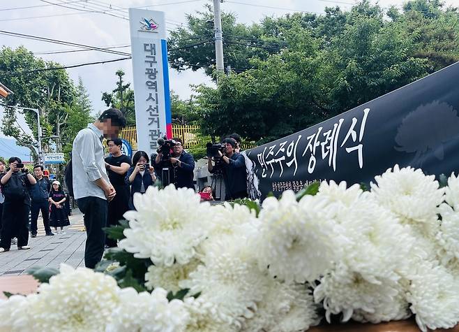 8일 오후 대구시선거관리위원회 앞에서 열린 ‘민주주의 장례식’에서 한 참석자가 헌화를 한 뒤 묵념을 하고 있다. /황인무 기자