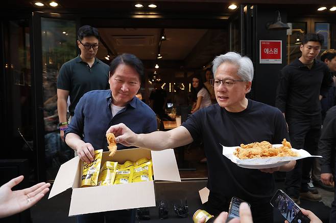 젠슨 황 엔비디아 최고경영자(CEO)와 최태원 SK그룹 회장이 7일 서울 강남구 깐부치킨 삼성점에서 치맥회동 도중 취재진에게 치킨과 HBM칩을 나눠주고 있다. /뉴시스