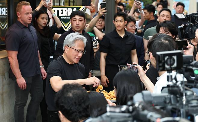 ▲ 젠슨 황 엔비디아 최고경영자(CEO)가 7일 서울 강남구 깐부치킨 삼성점에서 최태원 SK 회장과 치맥 회동을 하던 중 시민들에게 치킨을 나눠주고 있다. 연합뉴스