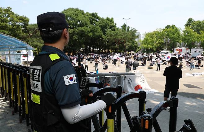 6·3 지방선거 투표용지 부족 사태를 규탄하며 재선거를 요구하는 ‘잠실 개표소 봉쇄 시위’가 계속되고 있는 9일 서울 송파구 올림픽공원 핸드볼경기장 출입구 앞에서 한 경찰이 집회를 지켜보고 있다. 연합뉴스