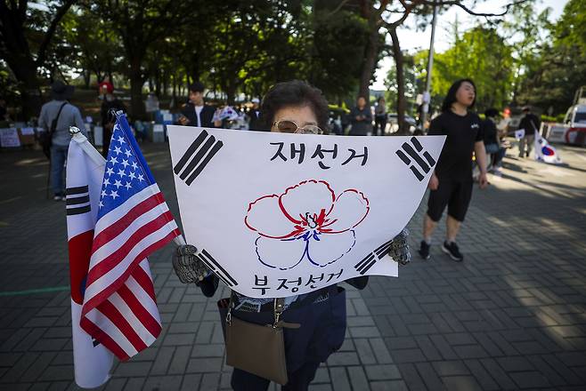 제9회 전국동시지방선거 투표용지 부족 사태에 항의하며 개표소 봉쇄 시위를 이어가는 시민들이 9일 서울 송파구 올림픽공원 핸드볼경기장에 설치된 개표소 앞에서 재선거를 촉구하며 피켓을 들고 있다. [뉴시스]