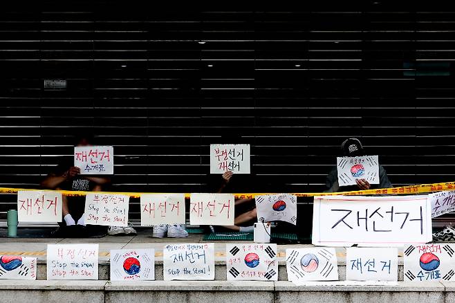 6·3 지방선거 투표용지 부족 사태를 규탄하며 재선거를 요구하는 '잠실 개표소 봉쇄 시위'가 계속되고 있는 9일 서울 송파구 올림픽공원 핸드볼경기장 출입구 앞에서 참가자들이 손팻말을 들고 있다. 연합뉴스