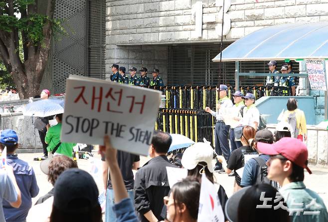 6·3 지방선거 투표용지 부족 사태를 규탄하고 재선거를 요구하는 '잠실 개표소 봉쇄 시위'가 나흘째 이어지고 있는 8일 서울 송파구 올림픽공원 핸드볼경기장 출입구 앞에서 시위 참가자들이 구호를 외치고 있다. 류영주 기자