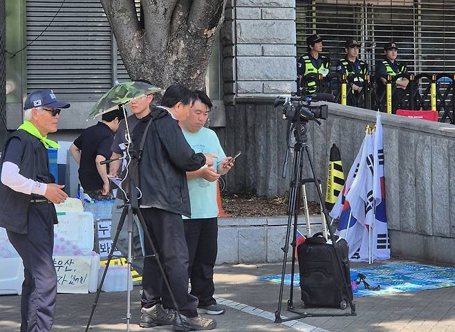 대만 매체인 중화텔레비전의 천졘안 영상기자가 9일 서울 송파구 올림픽공원 시위 현장에 취재왔다가 시위대로부터 국적, 시위 지지 여부 등에 대해 질문을 듣고 있는 모습. 차승윤 기자