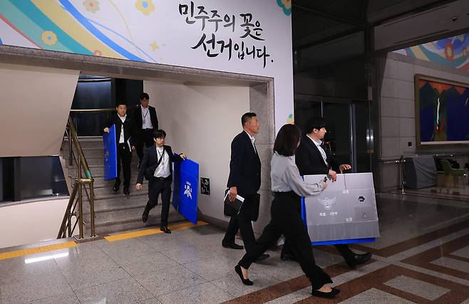 6·3 전국동시지방선거 투표용지 부족 사태를 들여다보고 있는 검경 합동수사본부 관계자들이 11일 경기도 과천 중앙선거관리위원회에서 압수수색을 마친 뒤 압수품을 들고 건물을 나서고 있다. /연합뉴스
