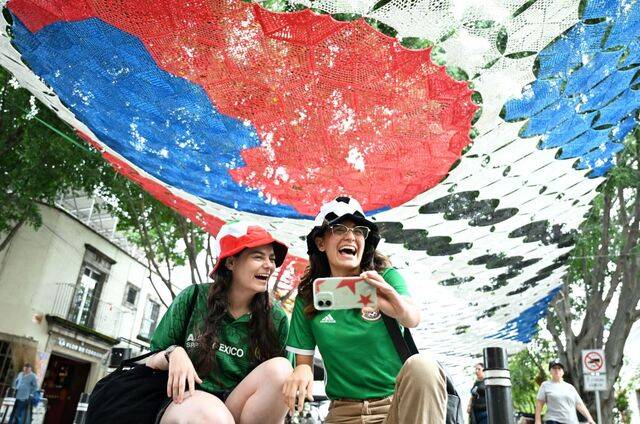 2026 국제축구연맹(FIFA) 북중미월드컵 개막을 이틀 앞둔 9일(현지시간) 멕시코 과달라하라 사포판 역사지구 보행자 전용 거리에서 멕시코 축구대표팀 유니폼을 입은 두 시민이 태극기 모양 현수막을 배경으로 사진을 찍고 있다. 과달라하라=이한형 기자