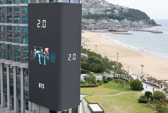 방탄소년단(BTS)의 공연을 앞두고 9일 부산 해운대해수욕장 앞 그랜드조선 호텔 외벽에 설치된 초대형 미디어 전광판에 BTS 뮤직비디오가 송출되고 있다. 연합뉴스