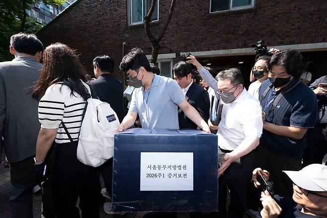 김지연 서울동부지방법원 부장판사와 관계자들이 10일 오후 6·3 지방선거 투표용지 부족 사태가 발생한 잠실7동 제2투표소였던 서울 송파구 우성아파트 노인정의 현장 검증을 마친 뒤 증거물을 들고 현장을 나서고 있다. 사진 장진영 기자