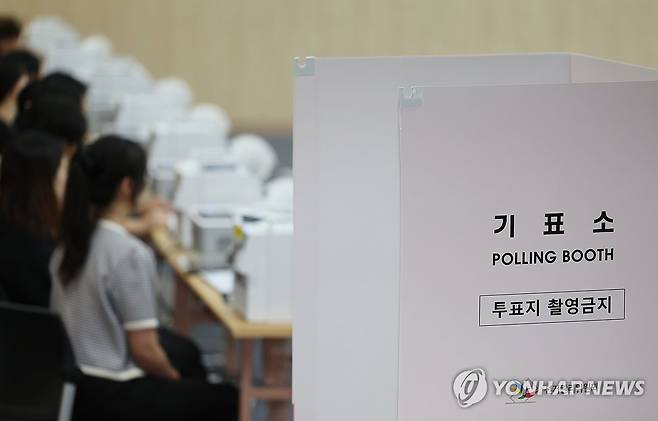 사전투표 준비하는 투표사무원들 (울산=연합뉴스) 김용태 기자 = 6·3 지방선거 사전투표를 하루 앞둔 28일 울산시 남구청 대강당에 마련된 사전투표소에 투표사무원들이 모의 투표를 하며 장비를 점검하고 있다. 2026.5.28 yongtae@yna.co.kr