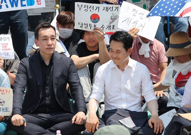 6·3지방선거 투표용지 부족 사태로 촉발된 잠실 개표소 봉쇄 시위가 이어진 16일 국민의힘 장동혁 대표, 김민수 최고위원이 서울 송파구 올림픽공원 핸드볼경기장 개표소 앞에 자리를 잡고 앉아 있다. [공동취재·연합뉴스]