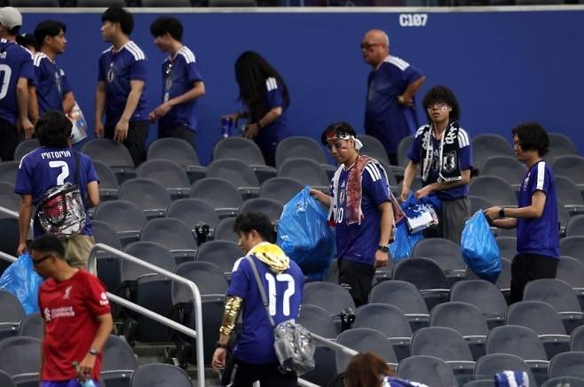 일본 축구팬들이 15일 북중미 월드컵 네덜란드전이 끝난 뒤 관중석 쓰레기를 치우고 있다. AFP연합뉴스