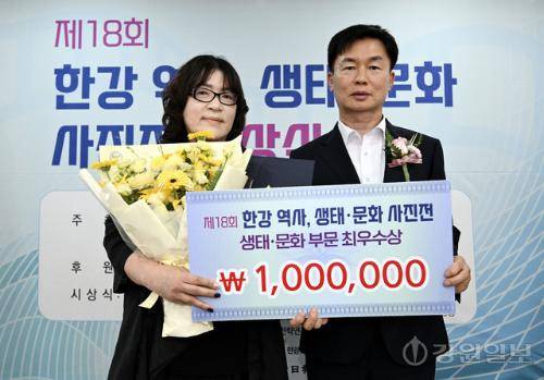 17일 춘천시 소양강댐 물 문화관에서 열린 제18회 한강 역사, 생태·문화 사진공모전 시상식에서 최우수상을 수상한 이영숙씨(왼쪽)가 윤승기 강원특별자치도 산림환경국장으로부터 축하 꽃다발을 전달받고 기념촬영을 하고 있다. 임도혁기자