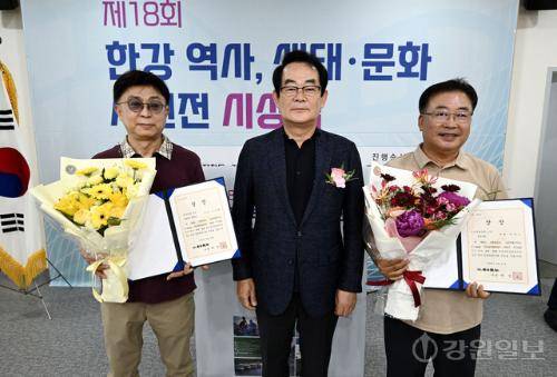 17일 춘천시 소양강댐 물 문화관에서 열린 제18회 한강 역사, 생태·문화 사진공모전 시상식에서 입선을 수상한 정운교(오른쪽 첫번째)·조강현(왼쪽 첫번째)씨가 박진오 강원일보 사장으로부터 축하 꽃다발을 전달받고 기념촬영을 하고 있다. 임도혁기자