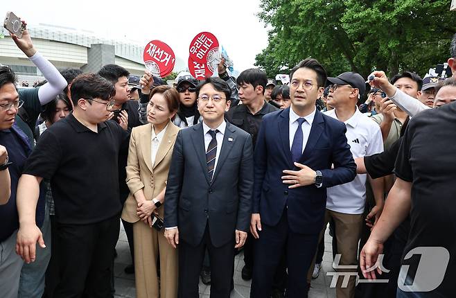 임오경, 천준호, 전용기 더불어민주당 의원이 17일 서울 송파구 올림픽공원 핸드볼경기장 앞에서 투표용지 부족 사태를 규탄하는 시민들에게 항의를 받으며 이동하고 있다. 2026.6.17 ⓒ 뉴스1 김도우 기자