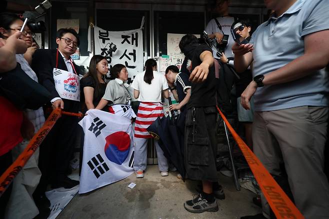서울 송파구 올림픽공원 핸드볼경기장이 봉쇄된 가운데 16일 시민 한 명이 문을 가로막아 체육회 인원들과 국민의힘 의원들이 건물 안으로 들어가지 못하고 있다. 강예진 기자