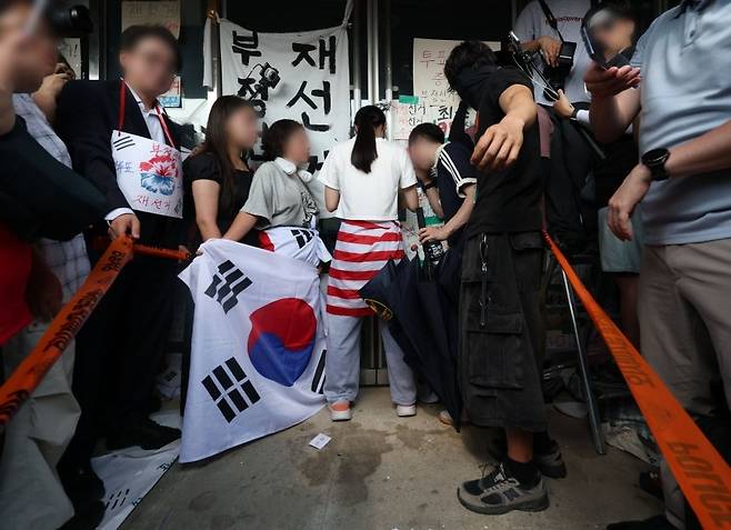 6·3 지방선거 투표용지 부족 사태로 시작한 서울 송파구 올림픽공원 핸드볼경기장 일대 ‘개표소 봉쇄 시위’가 이어진 16일 한 시위 참가자가 문을 가로막아 체육단체 직원들이 경기장 안으로 들어가지 못하고 있다. [연합뉴스]