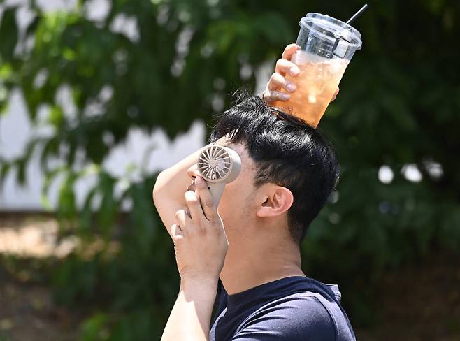 연일 무더위가 이어지고 있는 가운데 17일 경기 수원시 팔달구 인계동에서 한 시민이 손선풍기와 얼음이 들어있는 음료컵을 머리에 올리며 더위를 식히고 있다.(사진=뉴시스)