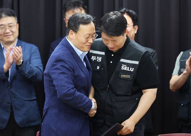 지난 5월20일 경기도 수원시 장안구 경기고용노동청에서 열린 삼성전자 임금협상을 마친 후 여명구 삼성전자 DS(디바이스솔루션·반도체 사업 담당) 피플팀장과 최승호 삼성그룹 초기업노동조합 삼성전자지부 위원장이 잠정 합의안에 서명한 후 손을 맞잡고 있다. 연합뉴스