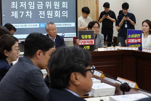 정부세종청사 최저임금위원회에서 18일 열린 제7차 전원회의에서 사용자 위원들이 최저임금의 업종별 구분적용을 요구하는 피켓을 들고 있다. 연합뉴스