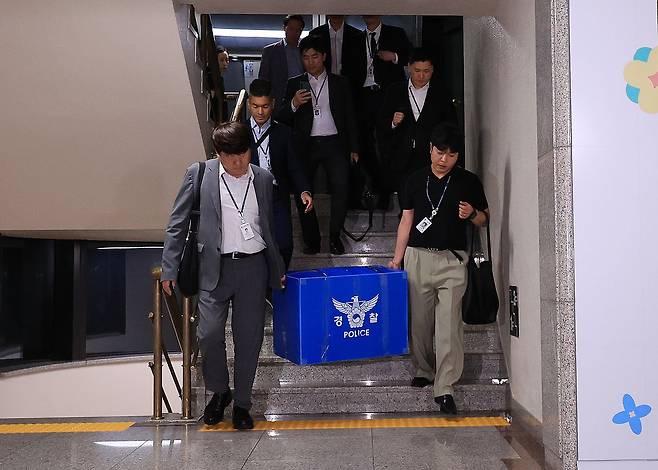 6·3 전국동시지방선거 투표용지 부족 사태를 들여다보고 있는 검경 합동수사본부 관계자들이 지난 11일 경기도 과천 중앙선거관리위원회에서 압수수색을 마친 뒤 압수품을 들고 건물을 나서고 있다. 연합뉴스