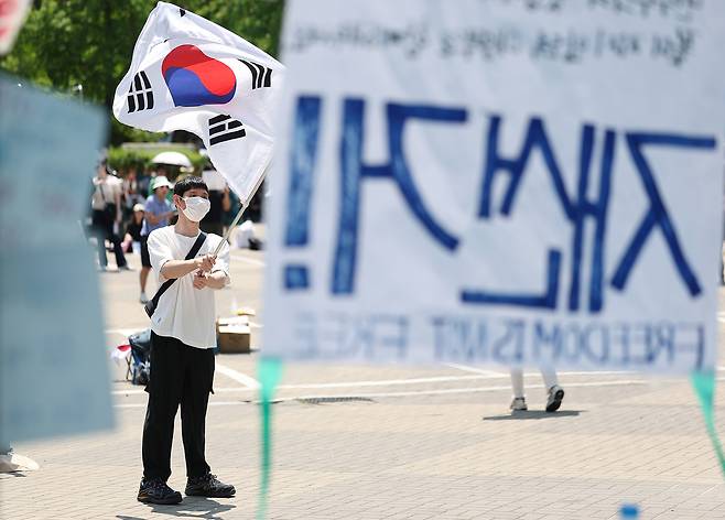 6·3 지방선거 투표용지 부족 사태를 규탄하며 재선거를 요구하는 ‘잠실 개표소 봉쇄 시위’가 계속되고 있는 6월 9일 서울 송파구 올림픽공원 핸드볼경기장에서 한 참가자가 태극기를 흔들고 있다. 연합뉴스