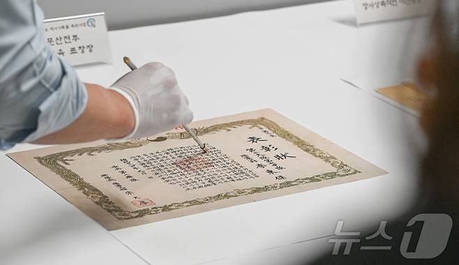 충남 계룡대 육군기록정보관리단(기정단)의 '중요 역사기록물 복원사업' 현장에서 기정단 관계자가 용문산전투 간 문맹 장병들에게 한글교육을 하면서 발행한 표창장을 보여주고 있다. (육군 제공. 재판매 및 DB 금지) 2025.6.24 ⓒ 뉴스1