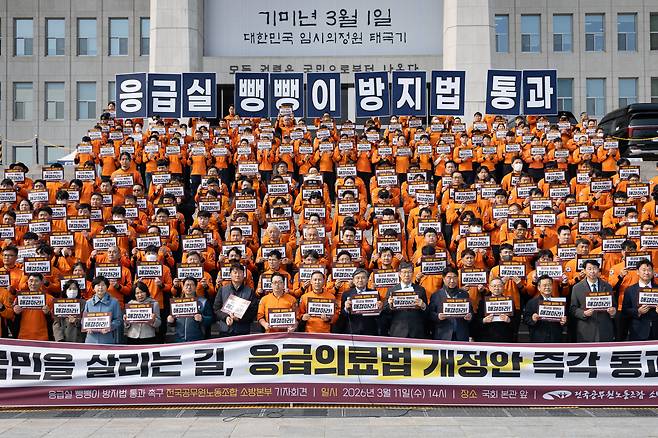 전국공무원노동조합 소방본부 조합원들과 여야 의원들이 3월 11일 서울 여의도 국회 본청 앞에서 열린 응급실 뺑뺑이 방지법(응급의료법 개정안) 통과 촉구 기자회견에서 구호를 외치고 있다. 2026.3.11/뉴스1