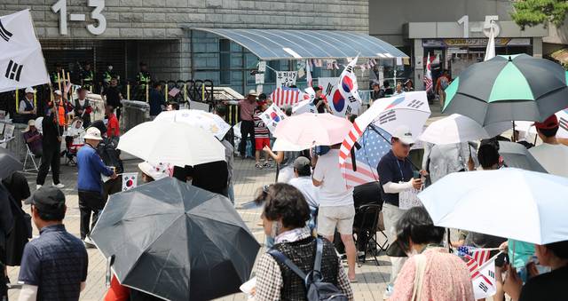 6·3 지방선거 당시 잠실 개표소로 사용된 서울 송파구 올림픽공원 핸드볼경기장 앞에서 28일 투표용지 부족 사태 규탄 봉쇄 시위 참가자들이 우산을 쓰고 구호를 외치고 있다.  [연합뉴스]