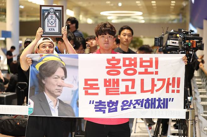 2026 북중미 월드컵 32강 진출에 실패해 한국 축구 국가대표팀에서 사퇴한 홍명보 전 감독이 입국하는 30일 인천국제공항 제2여객터미널을 찾은 팬들이 항의 현수막을 들어 올리고 있다. [연합뉴스]
