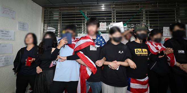 성조기 두르고 팔짱 꽉 6·3 지방선거 투표용지 부족 사태에 항의하며 개표소로 사용됐던 서울 송파구 올림픽공원 핸드볼경기장 봉쇄 시위를 하고 있는 시민들이 2일 ‘제9회 전국동시지방선거 투표용지 부족 사태 등 국민 참정권 침해 진상규명 및 선거관리 개혁을 위한 국정조사특별위원회’ 현장 조사를 막기 위해 출입문 앞에서 서로 팔짱을 끼고 서 있다.  연합뉴스