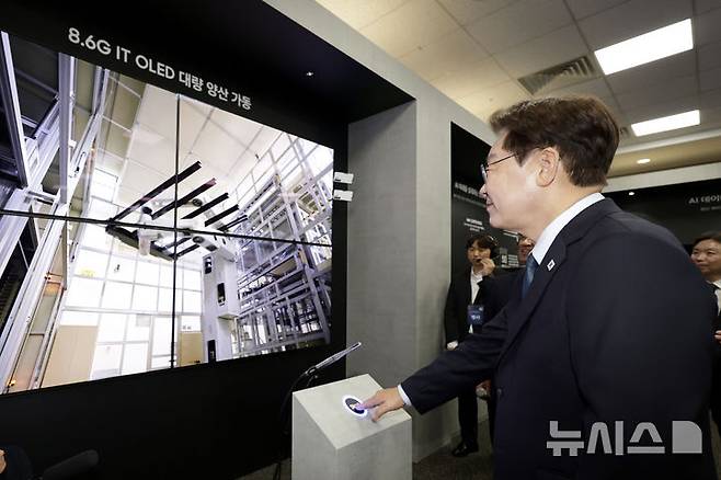 [아산=뉴시스] 최동준 기자 = 이재명 대통령이 2일 충남 아산시에서 열린 충청권  첨단산업 발전비전 국민보고회에서 삼성디스플레이의 주요 제품을 관람하며 유리 기판을 라인에 투입하는 버튼을 터치하고 있다.이 유리 기판은 세계 최초 8.6세대 OLED 디스플레이 양산을 위한 첫 투입이다. 2026.07.02. photocdj@newsis.com