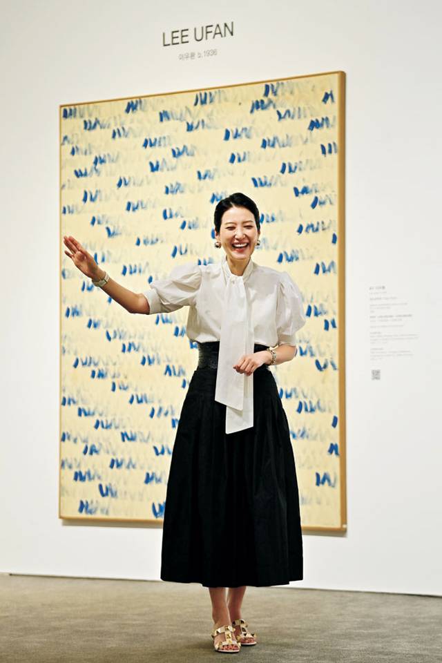 이우환의 ‘점으로부터’(1980) 앞에서 손 이사가 경매 진행 모습을 시연하며 웃고 있다. 이 작품도 15억 원에 팔렸다. 문호남 기자